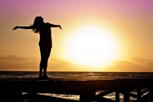 silhouette-of-woman-standing-on-pier-at-sunset